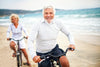 senior couple riding bikes along the beach.