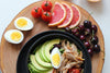 healthy foods displayed on a circular wooden cutting board.